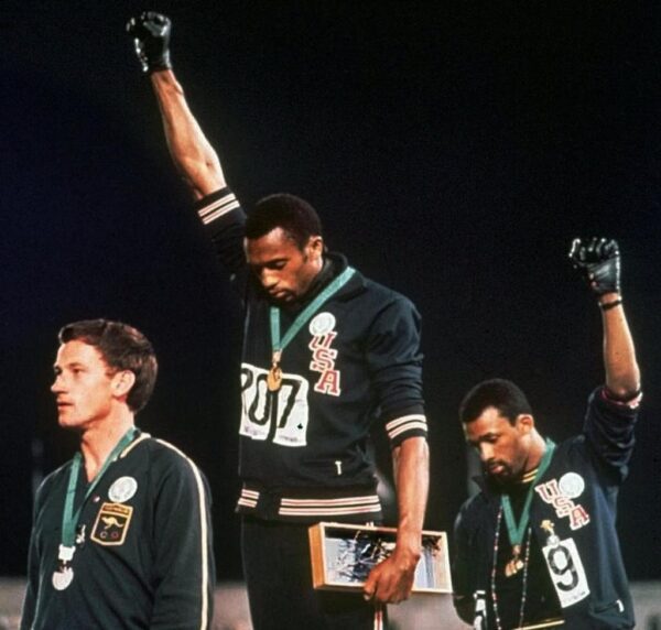Tommie Smith (c.) and John Carlos (r.) gave the black power salute after winning medals (AP)