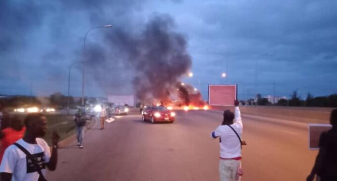 #BuhariMustGo protesters block Abuja airport road, set bonfire