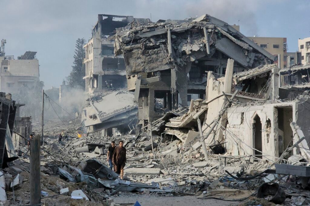 Palestinians walk through the rubble of buildings destroyed by Israeli airstrikes in Gaza City on Tuesday, Oct. 10, 2023. (AP Photo/Hassan Eslaiah)