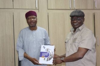 Kole Shettima, the country director of the MacArthur Foundation, receiving a copy of the "We the People Memorandum on Electoral Reforms" from Ezenwa Nwagwu, executive director of PAACA