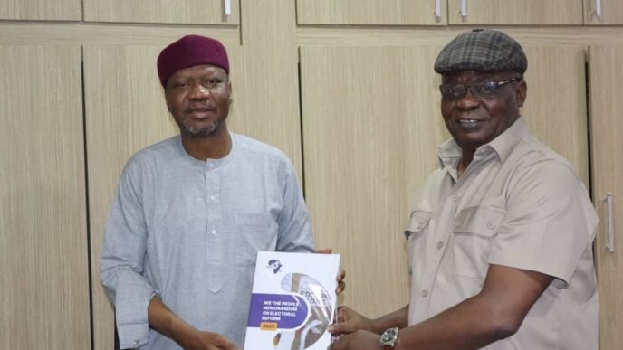 Kole Shettima, the country director of the MacArthur Foundation, receiving a copy of the "We the People Memorandum on Electoral Reforms" from Ezenwa Nwagwu, executive director of PAACA