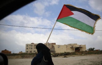 A Palestinian woman holds a Palestinian flag during a demonstration near the Gaza Strip border with Israel, in eastern Gaza City, Friday, March 30, 2018. (AP)
