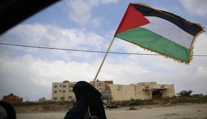 A Palestinian woman holds a Palestinian flag during a demonstration near the Gaza Strip border with Israel, in eastern Gaza City, Friday, March 30, 2018. (AP)